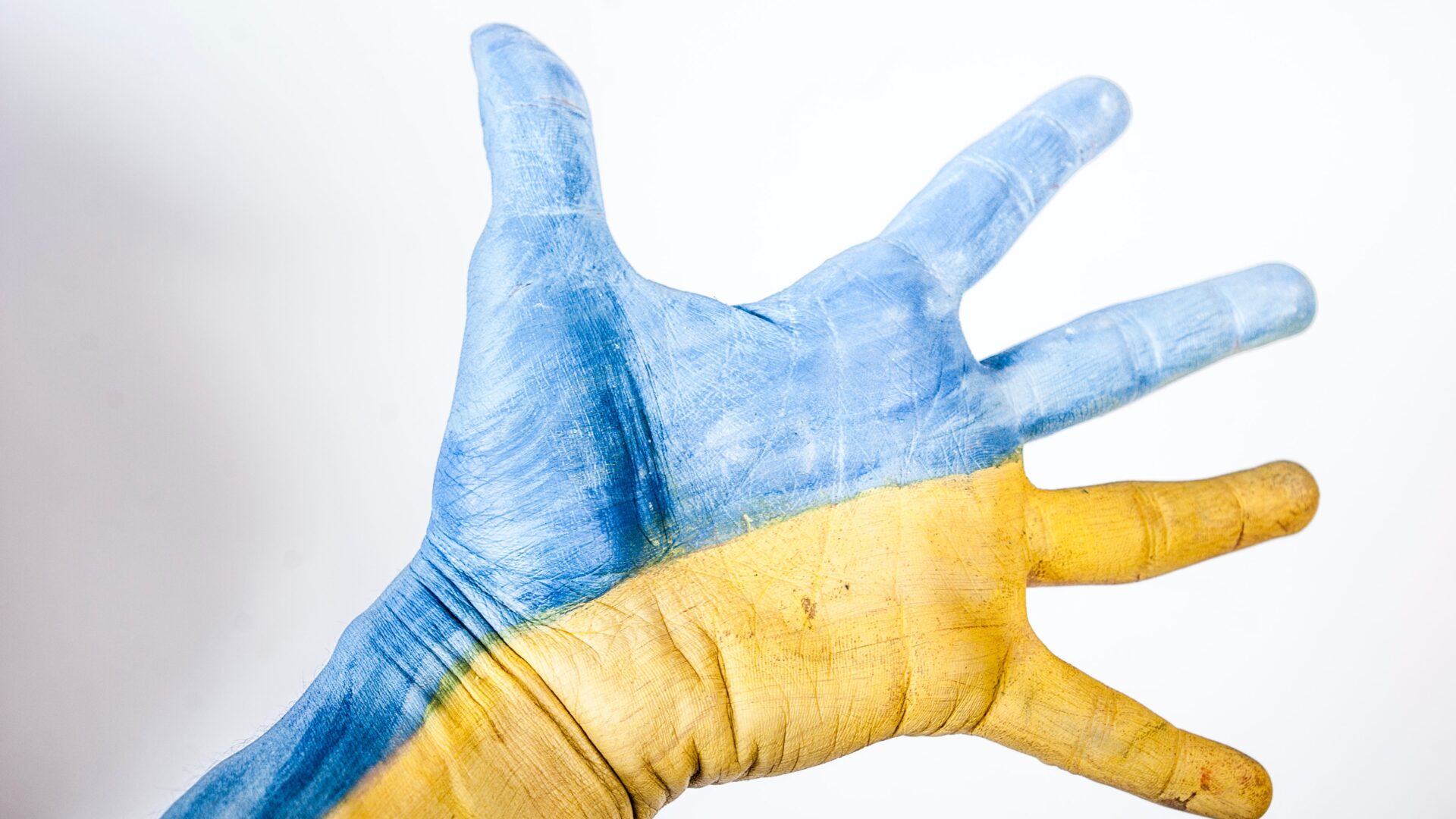 Eine Hand, gefärbt in Blau und Gelb, wird zur Unterstützung gereicht.