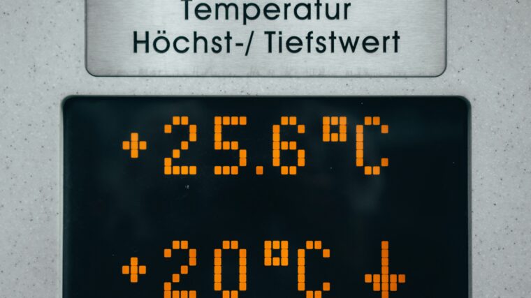 Digitale Anzeige mit der Beschriftung „Temperatur Höchst-/Tiefstwert“. Darunter leuchtet auf dem Display der Höchstwert mit +25,6 °C und der Tiefstwert mit +20 °C in orangefarbenen Pixelzahlen, begleitet von einem Abwärtspfeil.